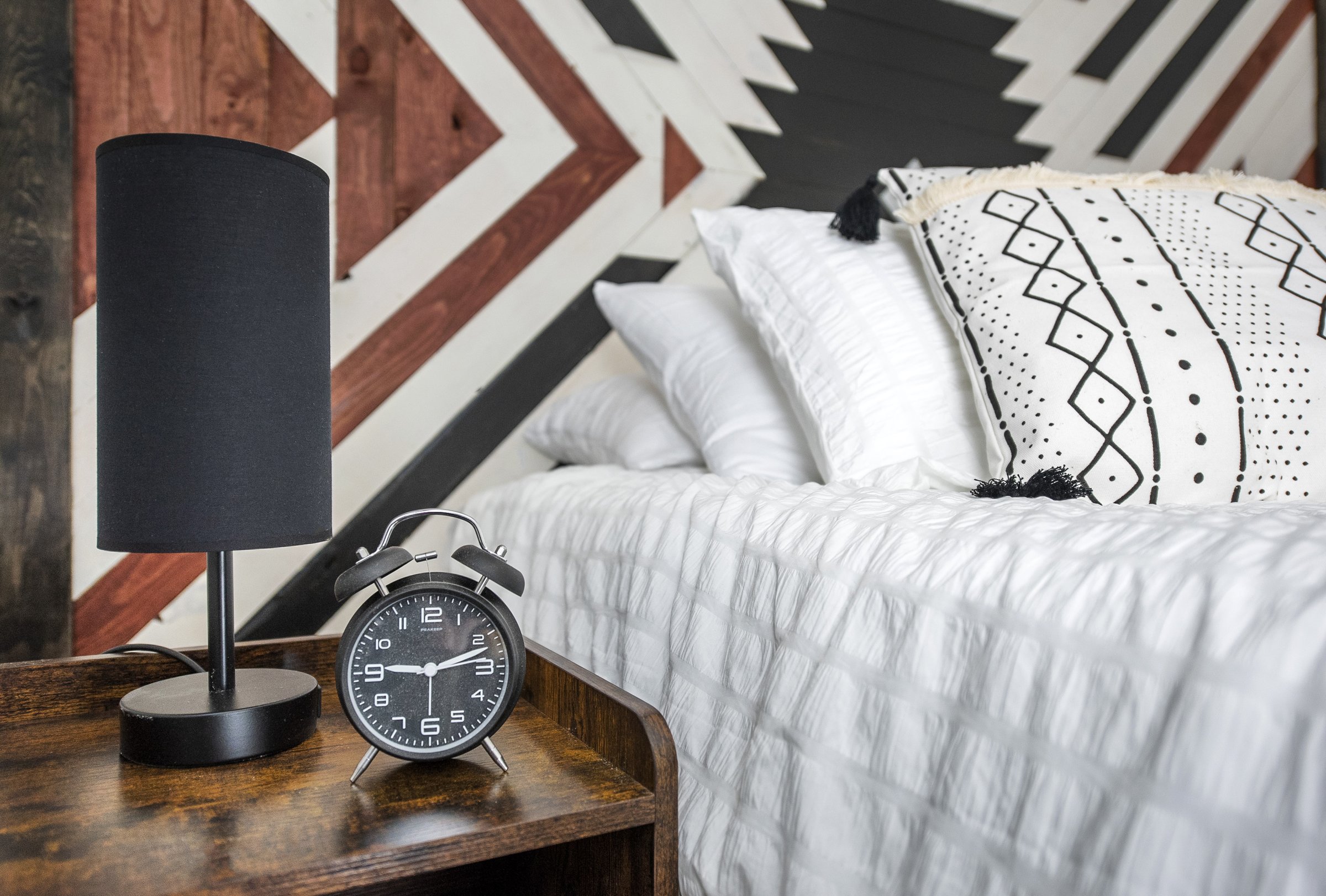 Bedside table, lamp, and geometric wood feature wall