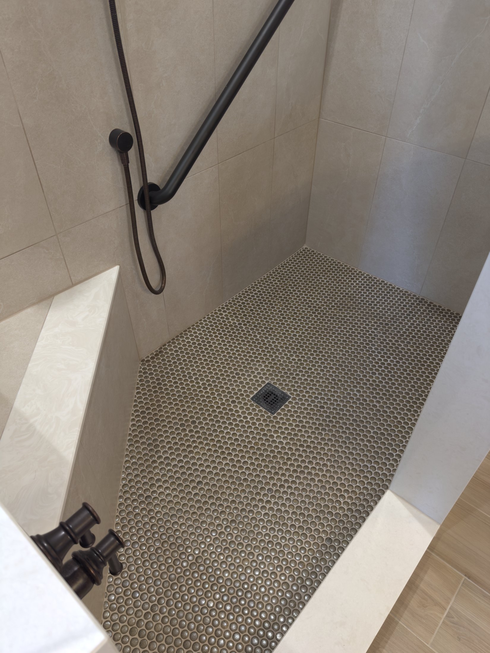 Walk-in shower with warm wall tile and a pebble mosaic floor